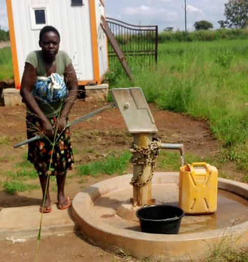 Woman pumping water at John's well